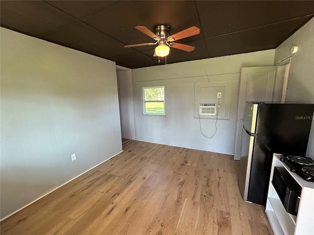 kitchen featuring range, stainless steel refrigerator, a wall unit AC, ceiling fan, and light hardwood / wood-style floors