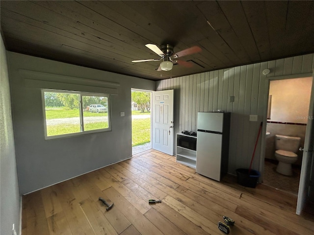 interior space featuring ceiling fan, wooden ceiling, stainless steel fridge, and light hardwood / wood-style floors