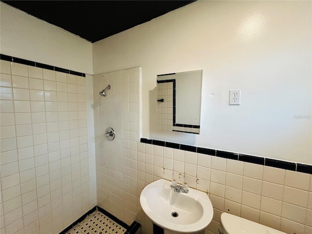 bathroom with toilet, sink, tile walls, and tiled shower