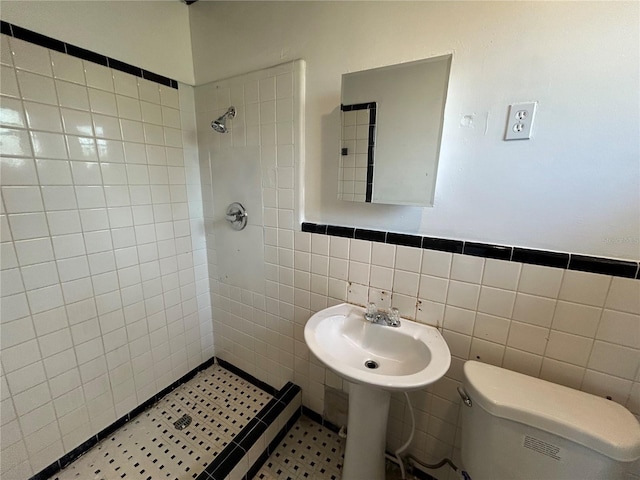 bathroom featuring tile walls, sink, toilet, and tiled shower