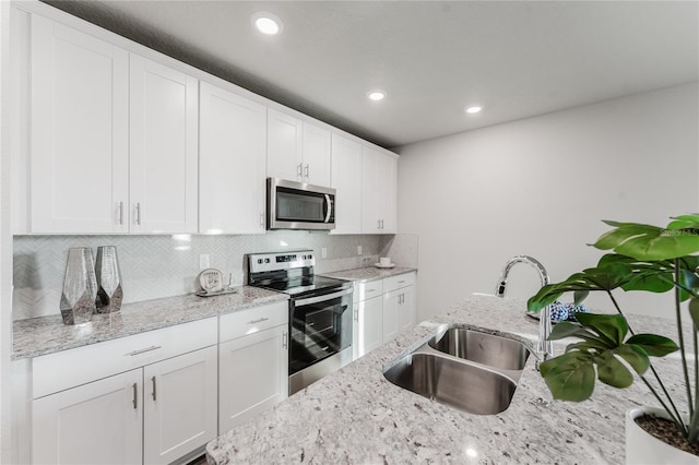 kitchen with white cabinetry, sink, stainless steel appliances, and light stone countertops