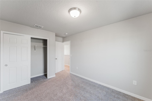 unfurnished bedroom with carpet, a textured ceiling, and a closet