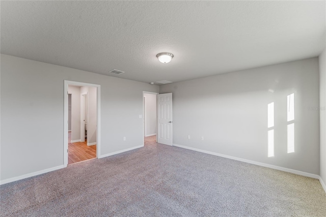 carpeted empty room featuring a textured ceiling