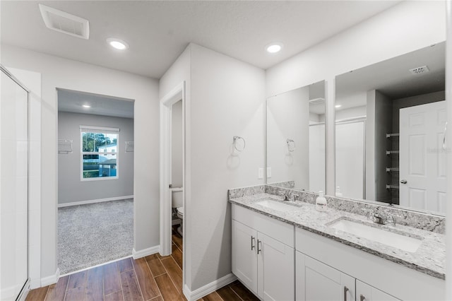 bathroom with hardwood / wood-style flooring, vanity, toilet, and an enclosed shower