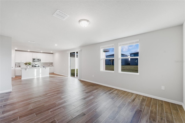 unfurnished living room with a textured ceiling and light wood-type flooring