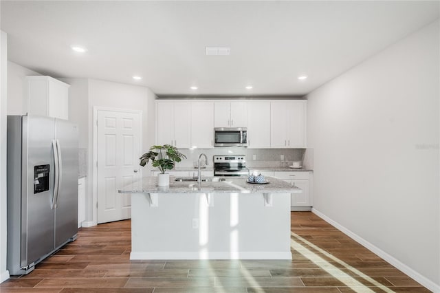 kitchen with stainless steel appliances, a kitchen island with sink, and white cabinets