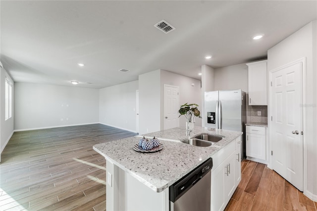 kitchen with white cabinetry, appliances with stainless steel finishes, sink, and a center island with sink