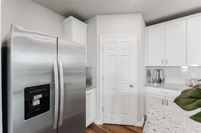 kitchen with white cabinetry, dark hardwood / wood-style floors, light stone countertops, and stainless steel fridge with ice dispenser