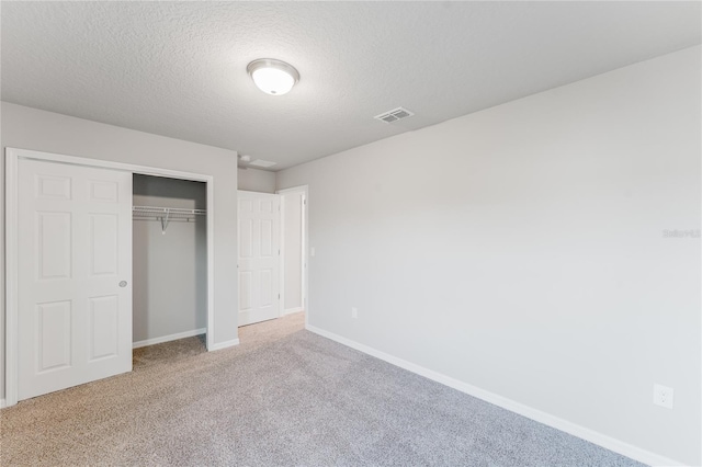 unfurnished bedroom featuring carpet, a textured ceiling, and a closet