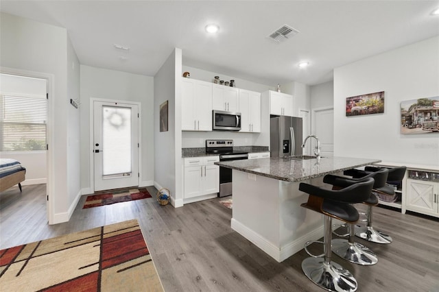 kitchen featuring white cabinetry, sink, dark stone countertops, a kitchen breakfast bar, and stainless steel appliances