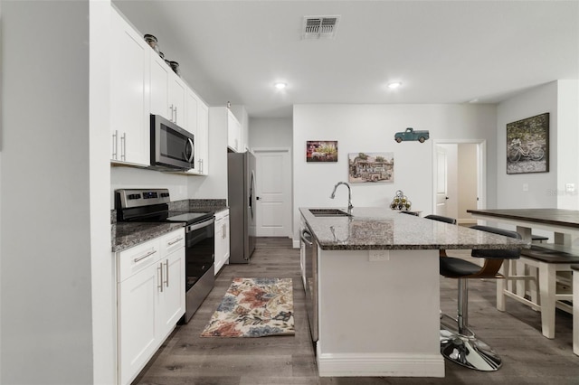 kitchen featuring sink, a breakfast bar area, stainless steel appliances, white cabinets, and a center island with sink