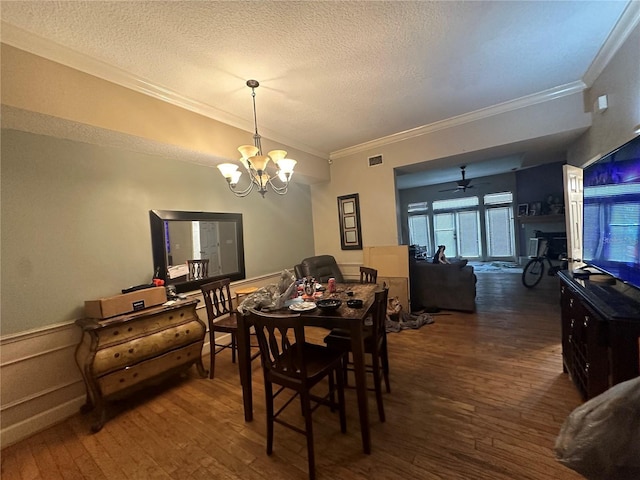 dining room featuring crown molding, dark hardwood / wood-style flooring, ceiling fan with notable chandelier, and a textured ceiling