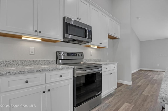 kitchen with white cabinetry, light stone countertops, light hardwood / wood-style floors, and appliances with stainless steel finishes