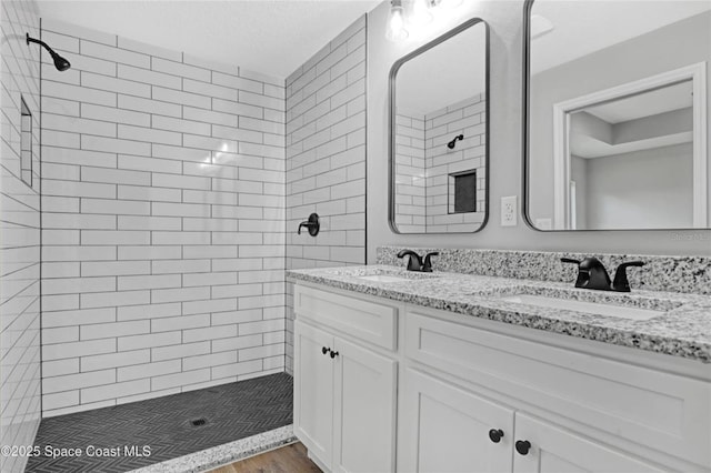 bathroom featuring hardwood / wood-style flooring, tiled shower, vanity, and a textured ceiling