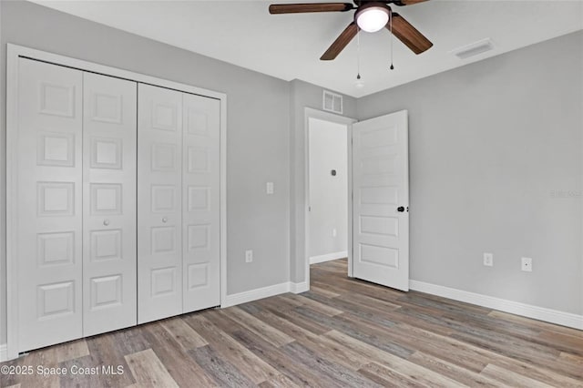 unfurnished bedroom with ceiling fan, light wood-type flooring, and a closet