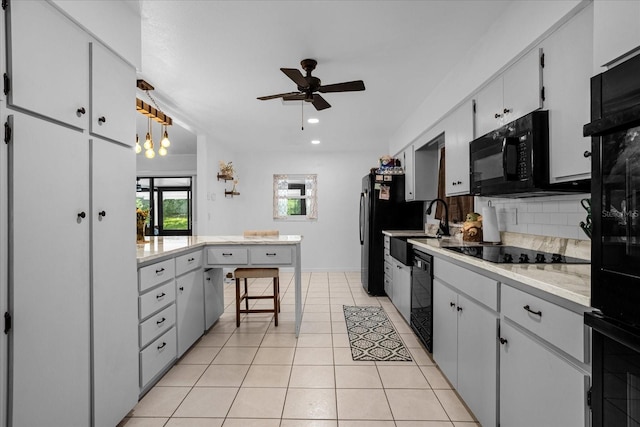 kitchen with black appliances, light tile patterned floors, a kitchen breakfast bar, pendant lighting, and backsplash