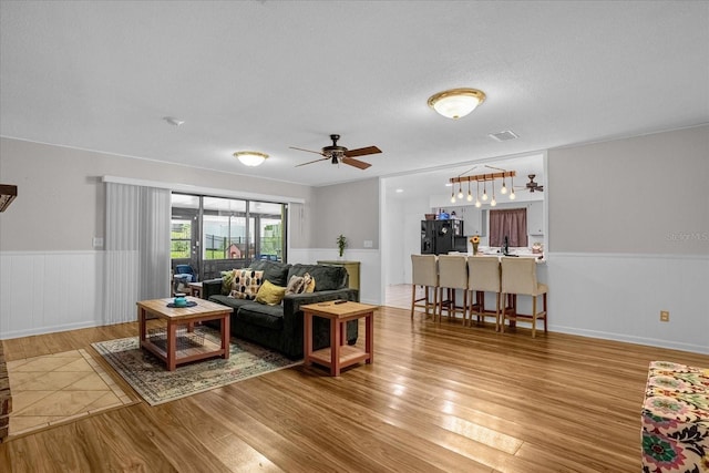 living room featuring ceiling fan, a textured ceiling, and light wood-type flooring