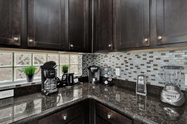 kitchen with dark brown cabinetry, backsplash, and dark stone counters