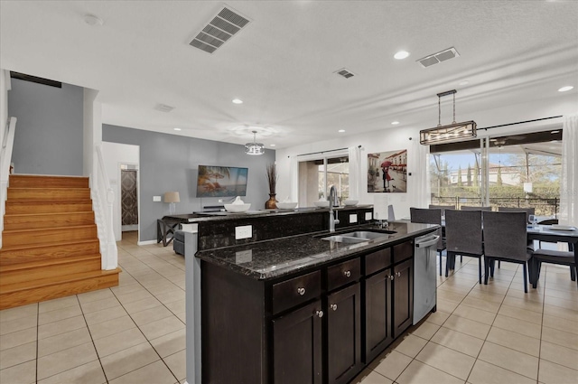 kitchen with decorative light fixtures, dishwasher, sink, dark stone counters, and light tile patterned floors