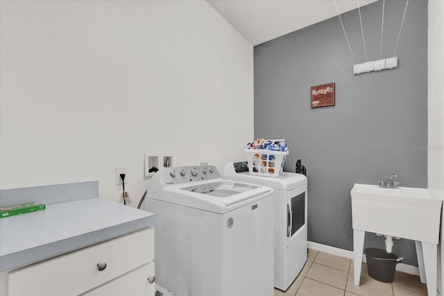 clothes washing area with separate washer and dryer, light tile patterned floors, and cabinets