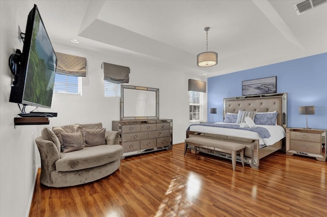 bedroom featuring hardwood / wood-style floors and a tray ceiling