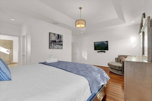 bedroom with hardwood / wood-style flooring and a raised ceiling