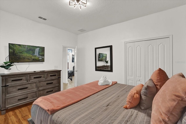 bedroom featuring light hardwood / wood-style floors, a closet, and a textured ceiling