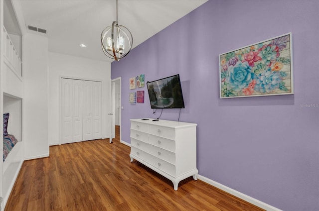 bedroom with hardwood / wood-style floors, a closet, and a chandelier