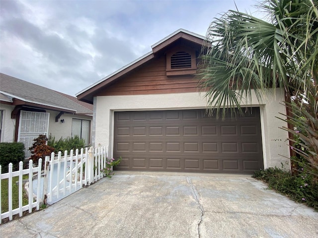 garage featuring fence and concrete driveway