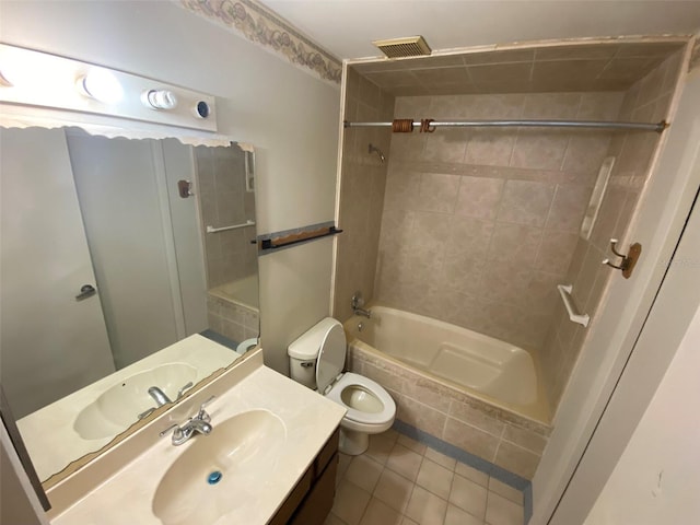 bathroom with tile patterned floors, toilet, vanity, and tiled shower / bath