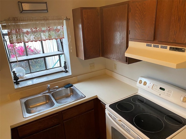 kitchen featuring white range with electric cooktop, under cabinet range hood, light countertops, and a sink