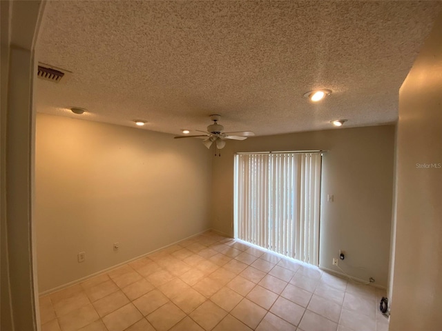 spare room with light tile patterned floors, ceiling fan, visible vents, baseboards, and a textured ceiling