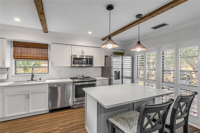 kitchen with sink, hanging light fixtures, white cabinets, and appliances with stainless steel finishes