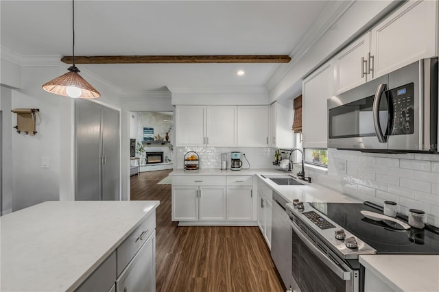 kitchen featuring sink, beam ceiling, stainless steel appliances, white cabinets, and decorative light fixtures