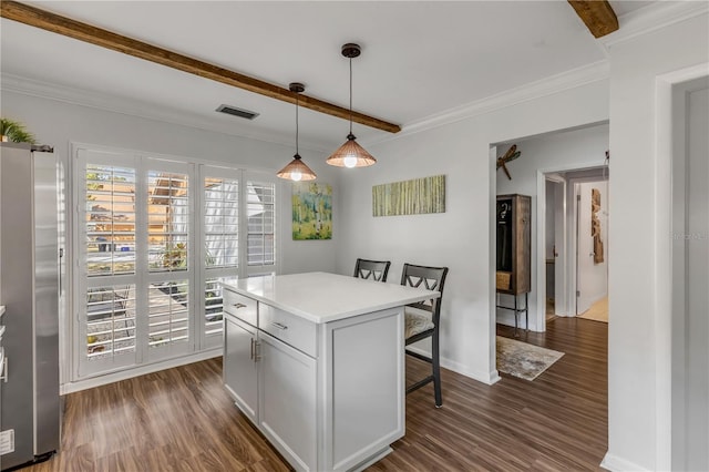 kitchen with dark wood-type flooring, stainless steel refrigerator, a center island, a kitchen bar, and decorative light fixtures