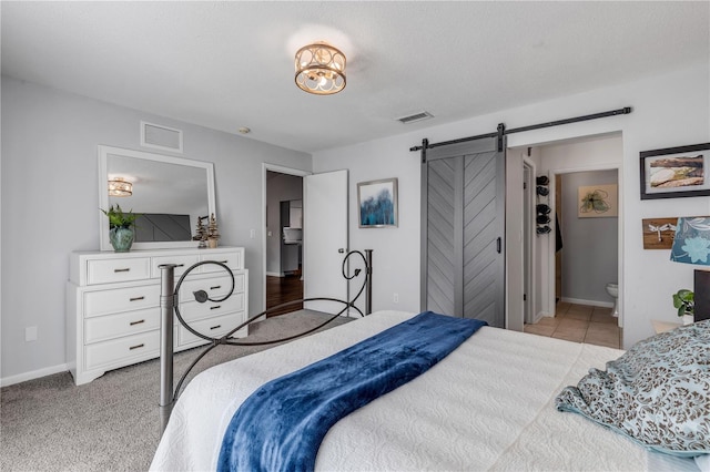 carpeted bedroom with connected bathroom and a barn door