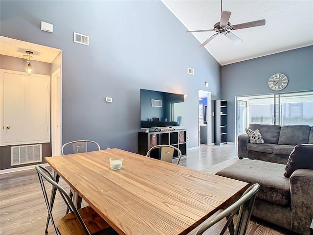 dining space with ceiling fan, high vaulted ceiling, and light wood-type flooring