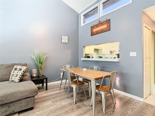 dining area featuring wood-type flooring and a high ceiling