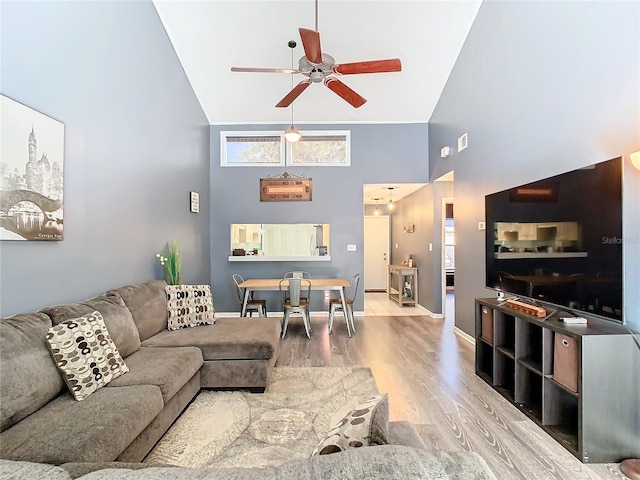 living room featuring a towering ceiling, ceiling fan, and light hardwood / wood-style flooring