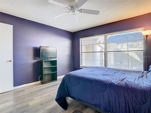 bedroom featuring hardwood / wood-style flooring, ceiling fan, and a textured ceiling