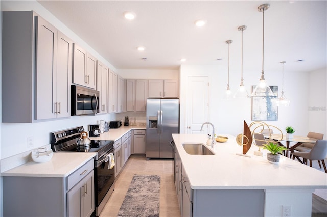 kitchen with pendant lighting, an island with sink, stainless steel appliances, and sink