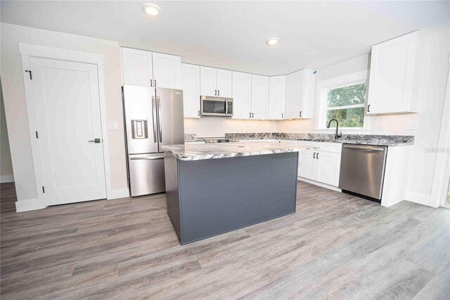 kitchen with sink, white cabinetry, a center island, stainless steel appliances, and light stone countertops