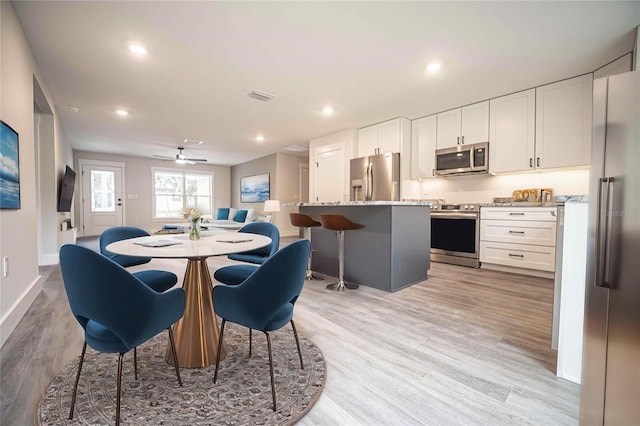 dining area with light hardwood / wood-style floors and ceiling fan