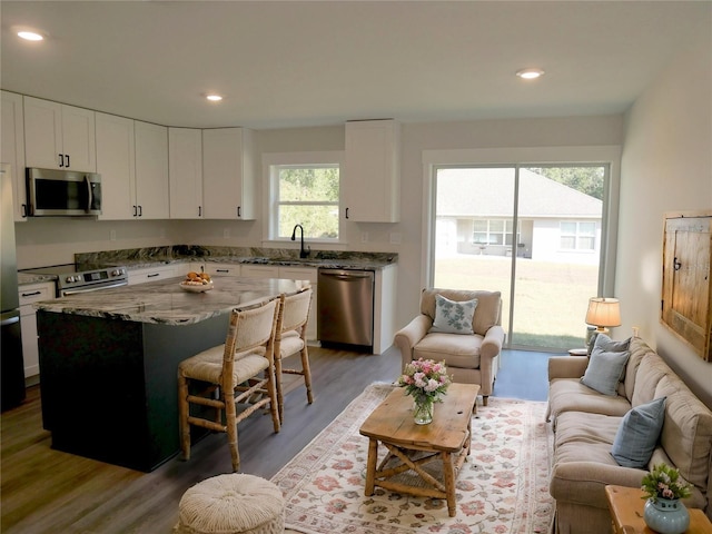 kitchen featuring sink, white cabinetry, light stone counters, a center island, and appliances with stainless steel finishes