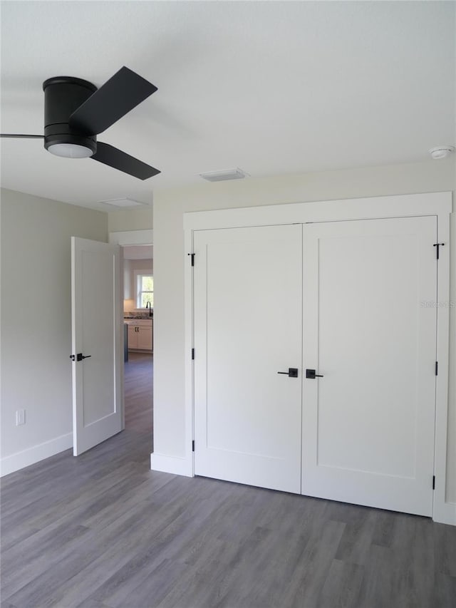 unfurnished bedroom with dark hardwood / wood-style flooring, a closet, and ceiling fan