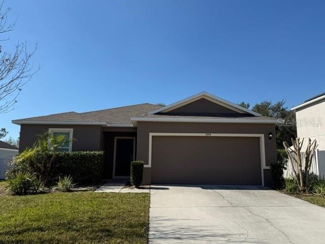 single story home featuring a garage and a front yard