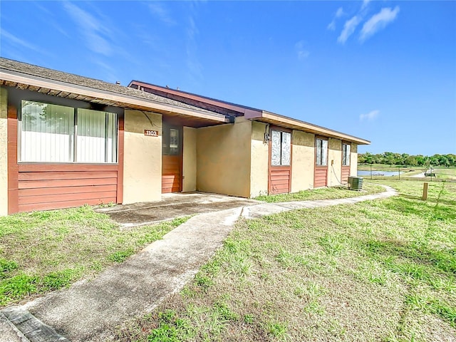 view of front facade with central AC and a front lawn