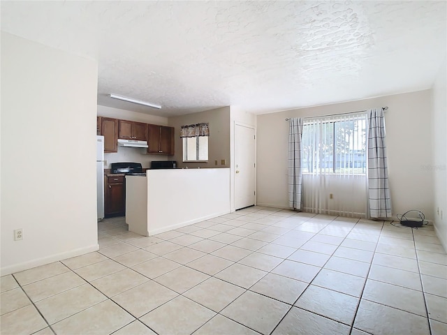 kitchen featuring light tile patterned floors, a textured ceiling, and refrigerator