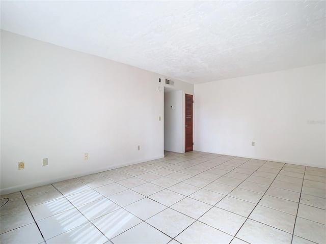 tiled empty room featuring a textured ceiling