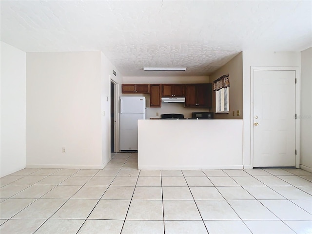 kitchen with light tile patterned flooring, white fridge, and a textured ceiling